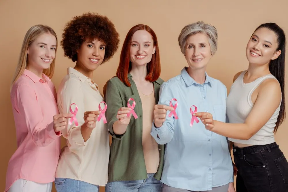 Grupo de mulheres reunidas segurando símbolo do outubro rosa que se trata sobre a conscientização do câncer de mama.