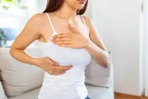 Mulher apalpando peito para verificar se existe algum nódulo sólido na mama.