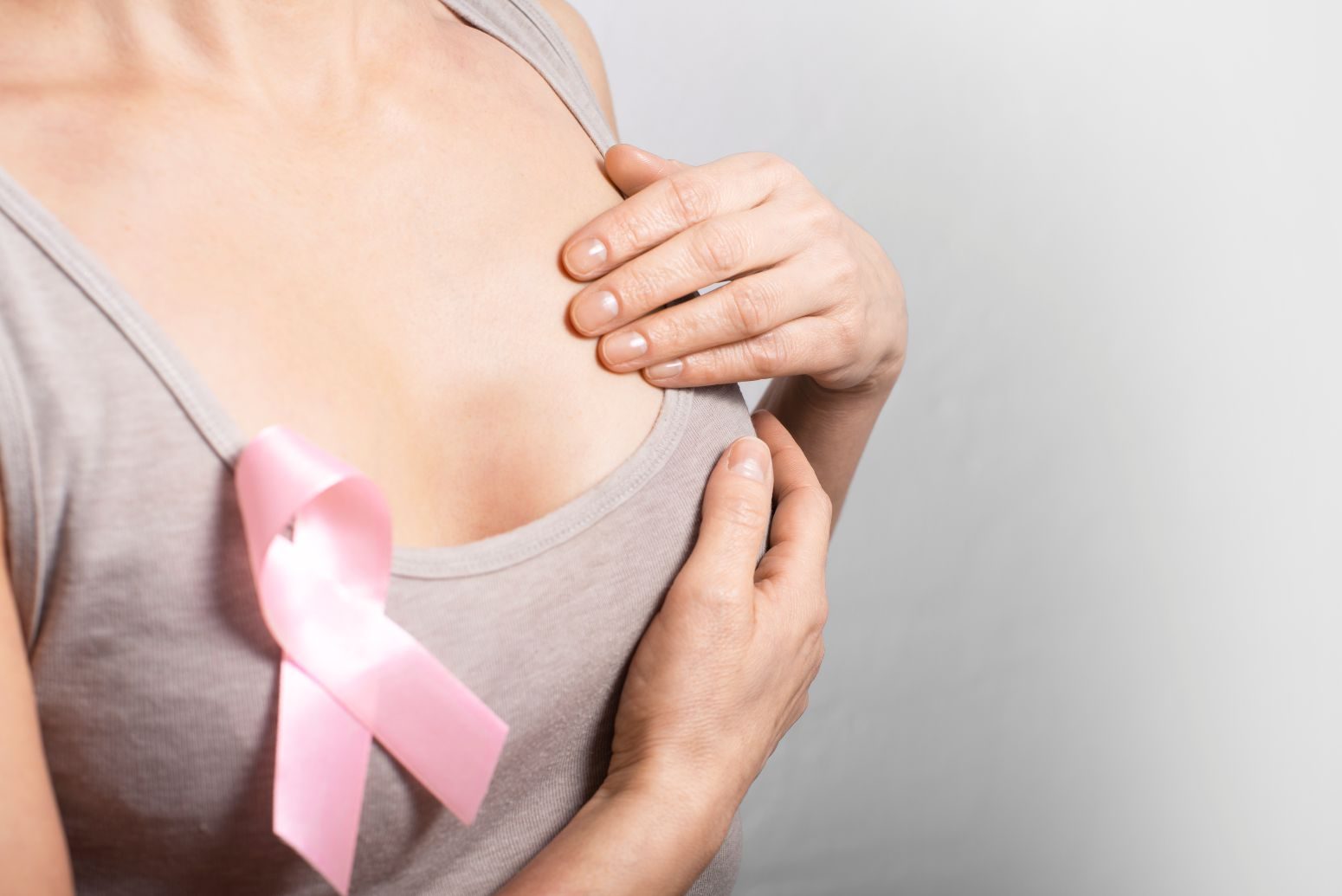 Mulher apalpando nódulo benigno na mama para saber de precisa ser retirado.
