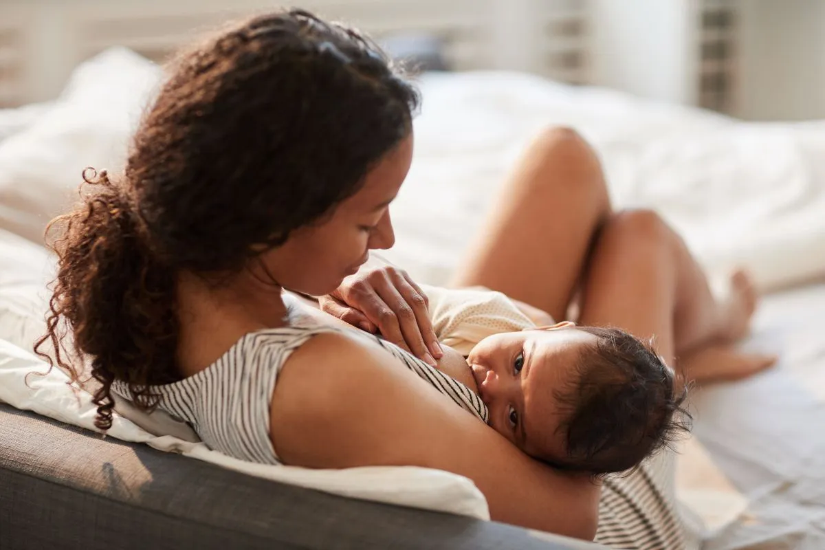 Mãe amamentando bebê em ambiente tranquilo, representando atenção aos sinais de câncer de mama em quem amamenta.